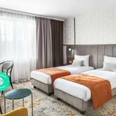Pokój hotelowy z dwoma łóżkami, oknem i miejscem do pracy. Dowiedz się, ile kosztuje nocleg w Krakowie, szukając komfortowych opcji.