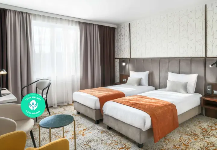 Pokój hotelowy z dwoma łóżkami, oknem i miejscem do pracy. Dowiedz się, ile kosztuje nocleg w Krakowie, szukając komfortowych opcji.