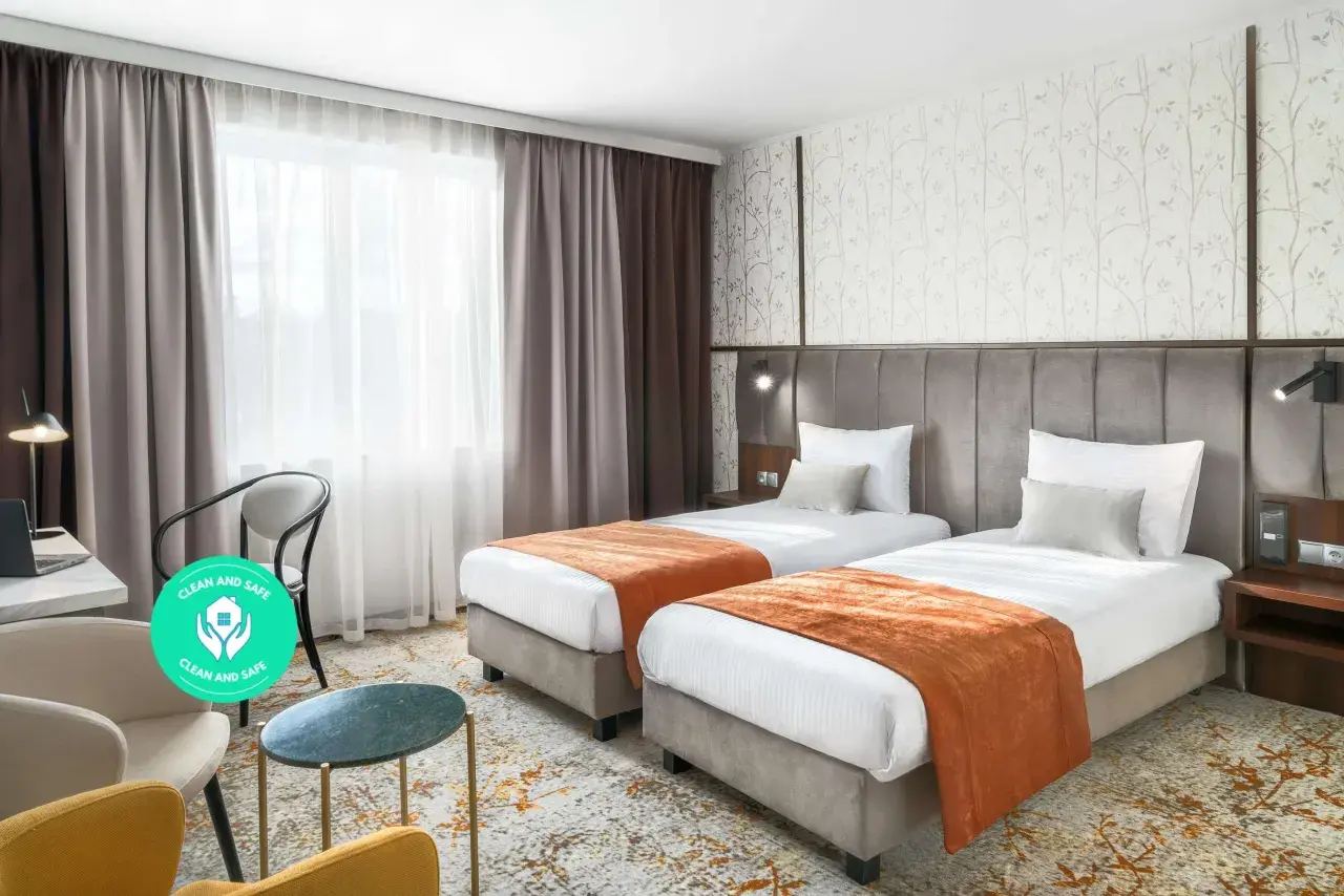 Pokój hotelowy z dwoma łóżkami, oknem i miejscem do pracy. Dowiedz się, ile kosztuje nocleg w Krakowie, szukając komfortowych opcji.