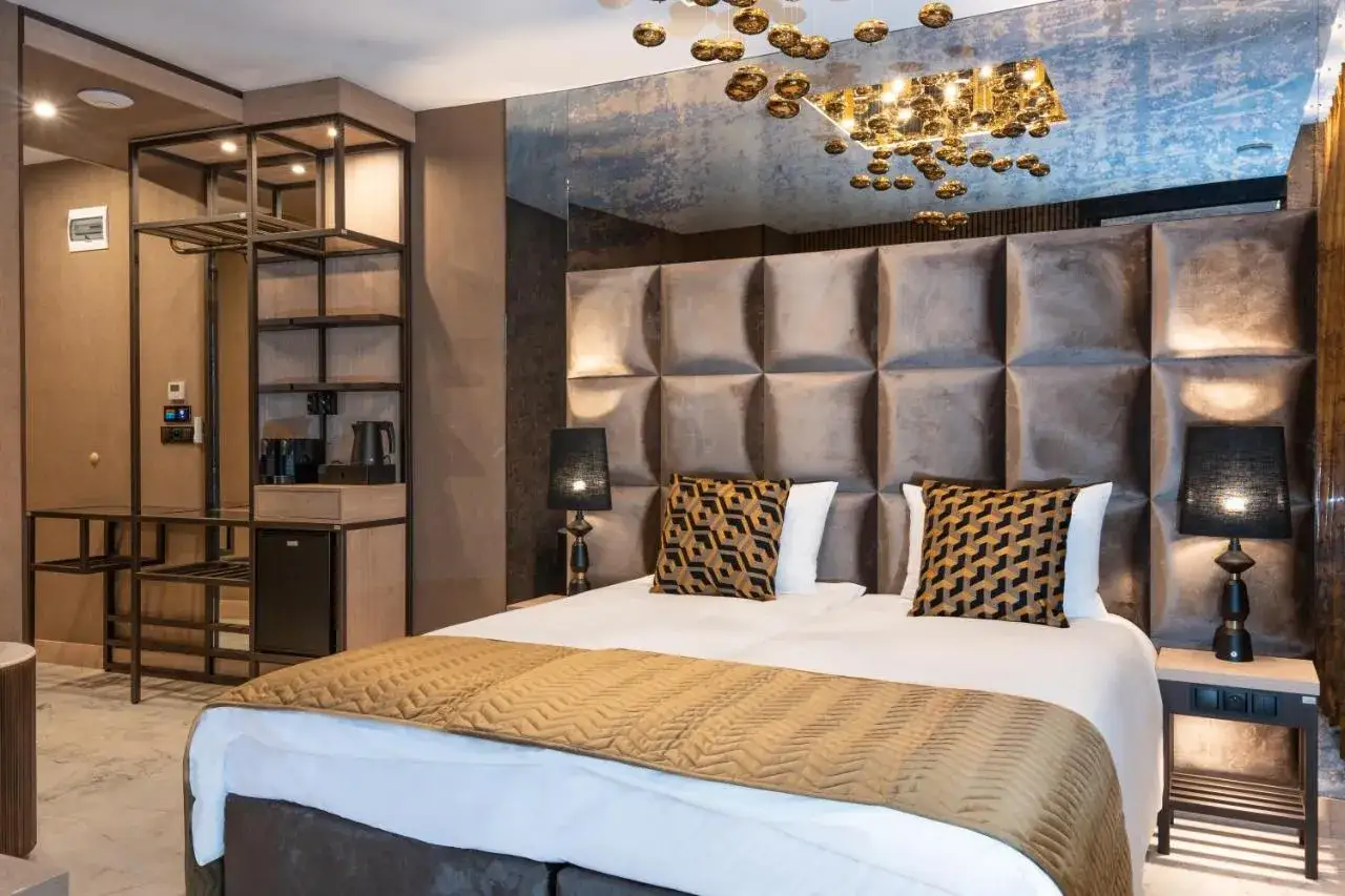 Elegancki pokój hotelowy z dużym łóżkiem i ozdobnym zagłówkiem. Zastanawiasz się, ile kosztuje nocleg w Krakowie?